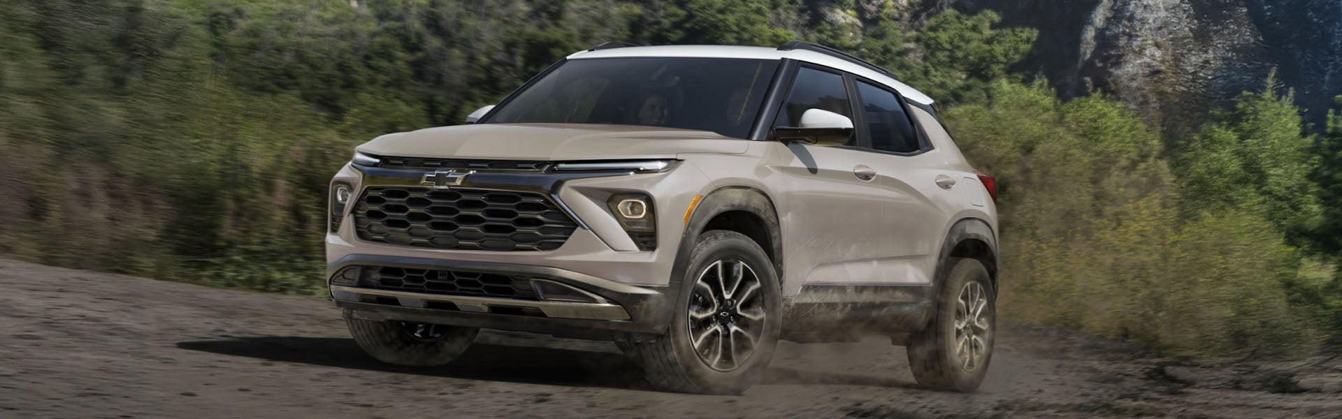 a blue trailblazer parked next to an office building with 2 people walking towards the vehicle.