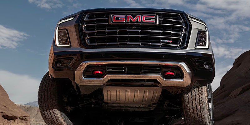 A GMC Yukon sitting parked with the front end in the air.