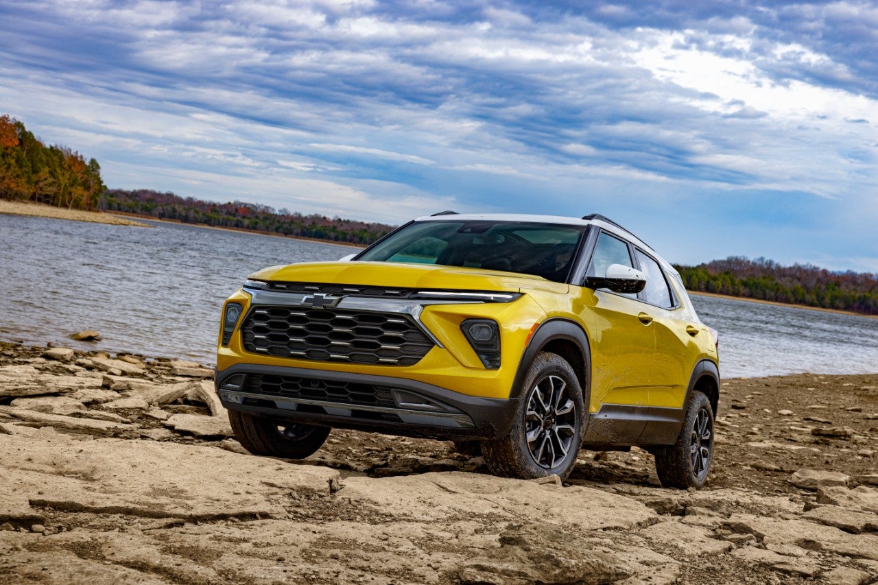 a yellow 2025 trailblazer parked on a rocky terrain near a lake