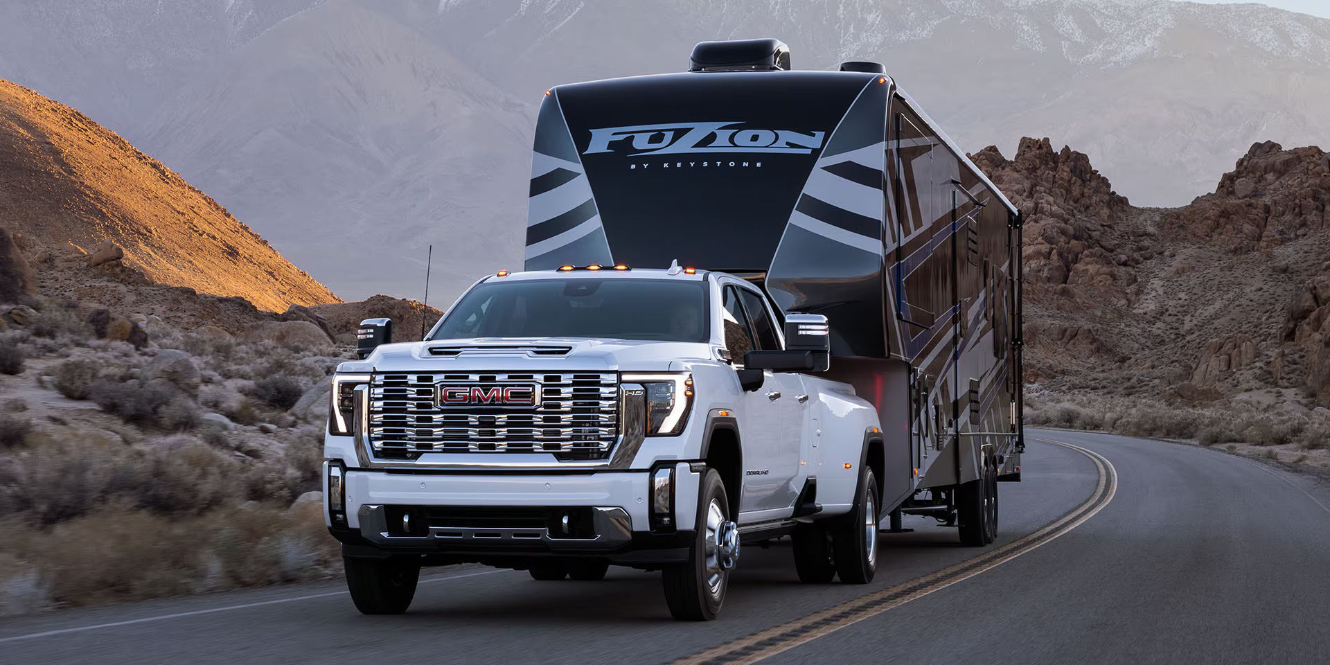 a white sierra hd truck hauling a larger camper trailer