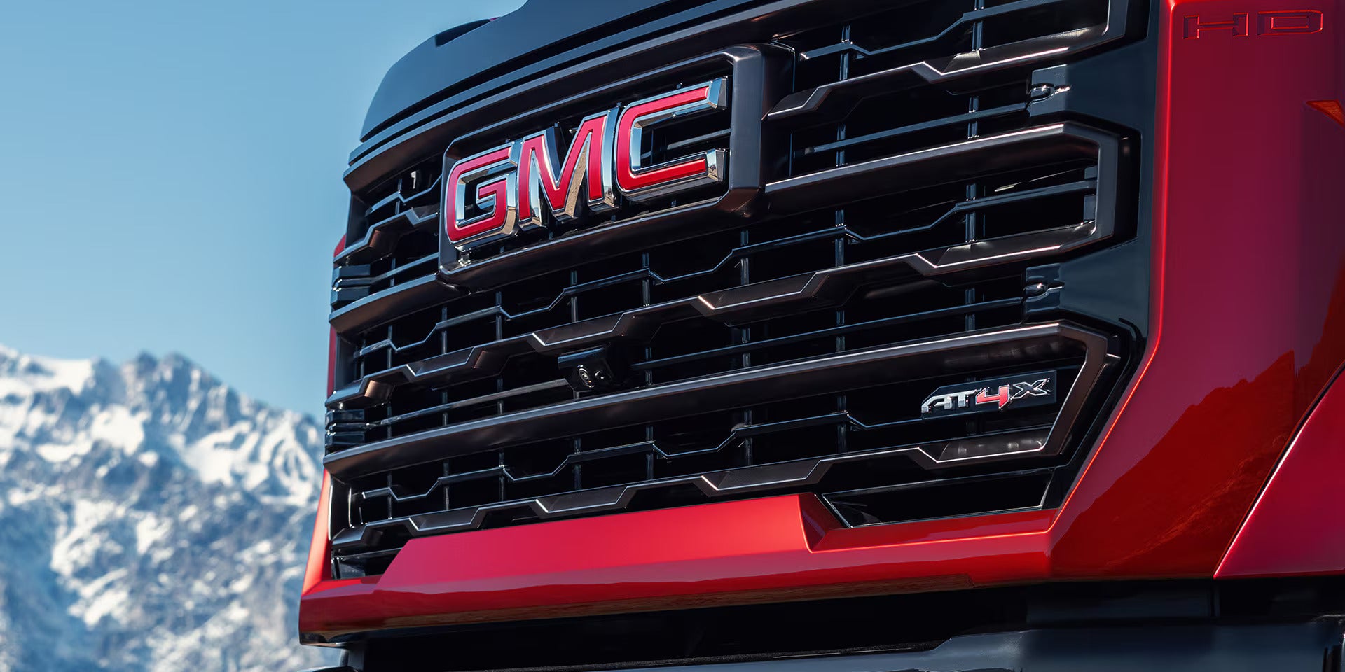 a red 2025 sierra hd up close on the grille showcasing the AT4X badging