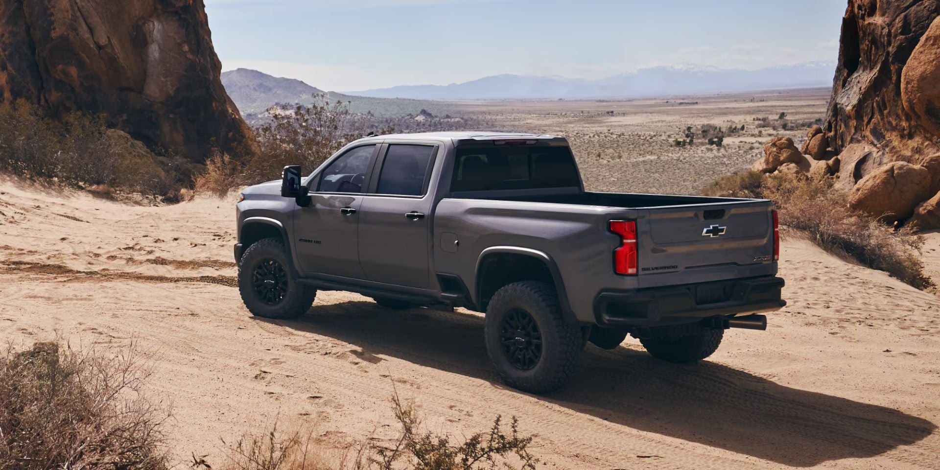 a dark grey 2025 silverado hd parked on sand next to water