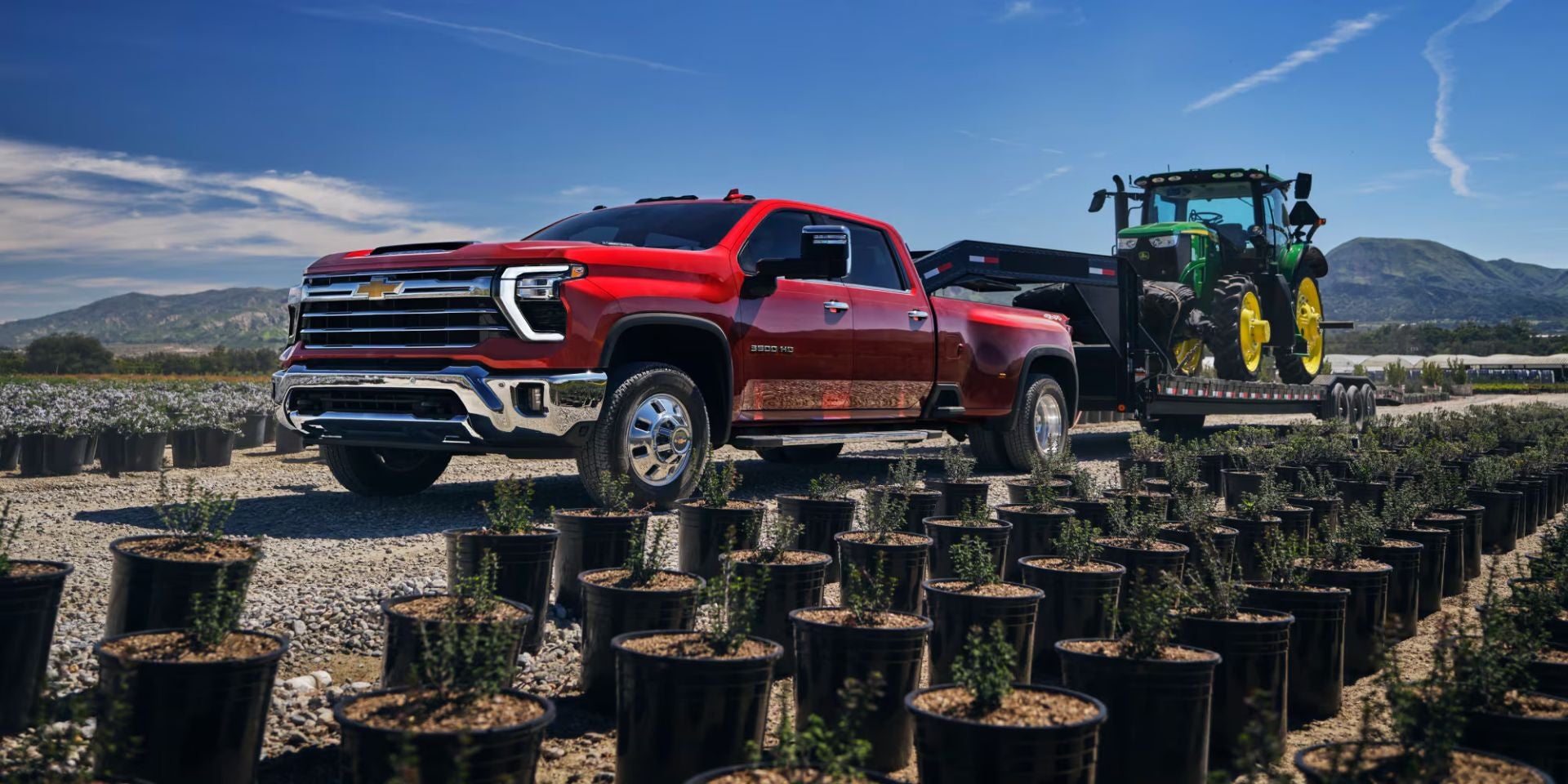 a red silverado 3500 hauling a tractor