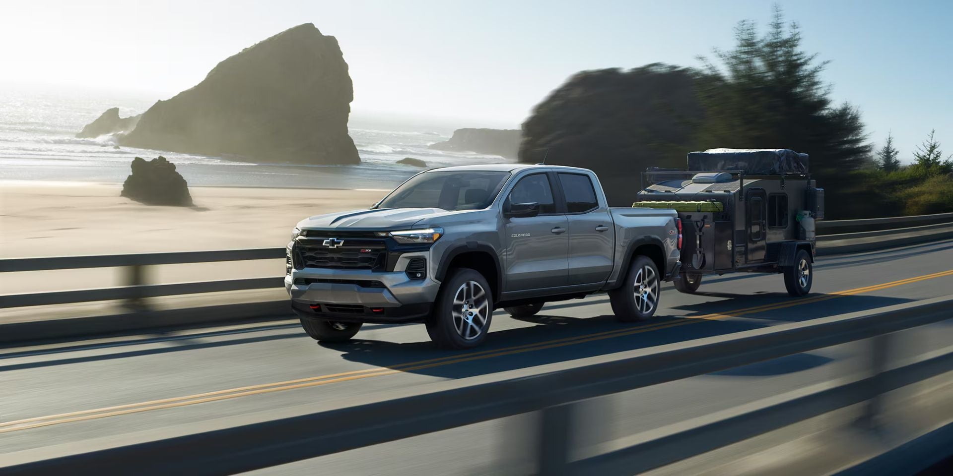 A gray truck pulling a trailer on the road.