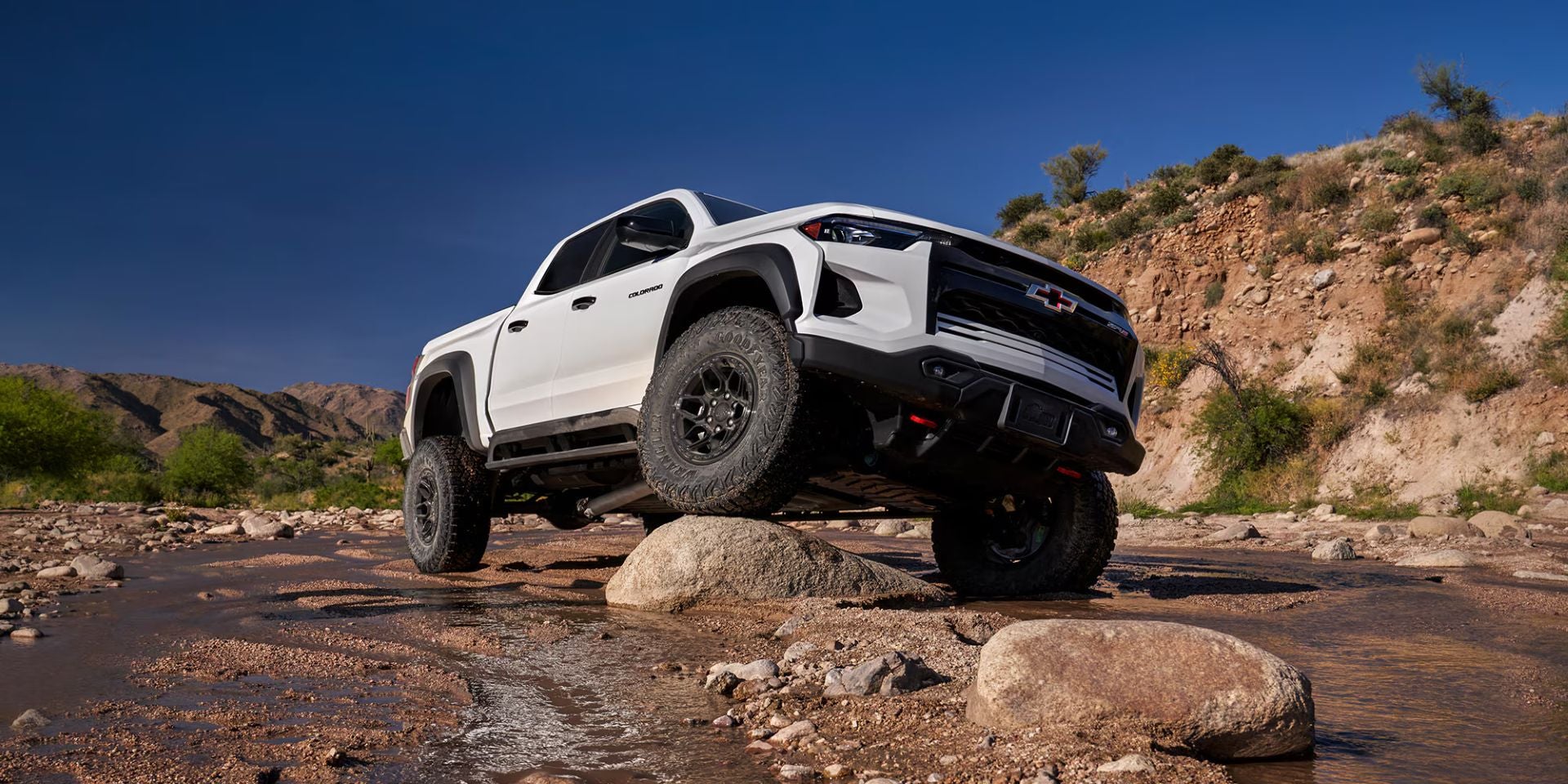 A white truck drove up on a rock.
