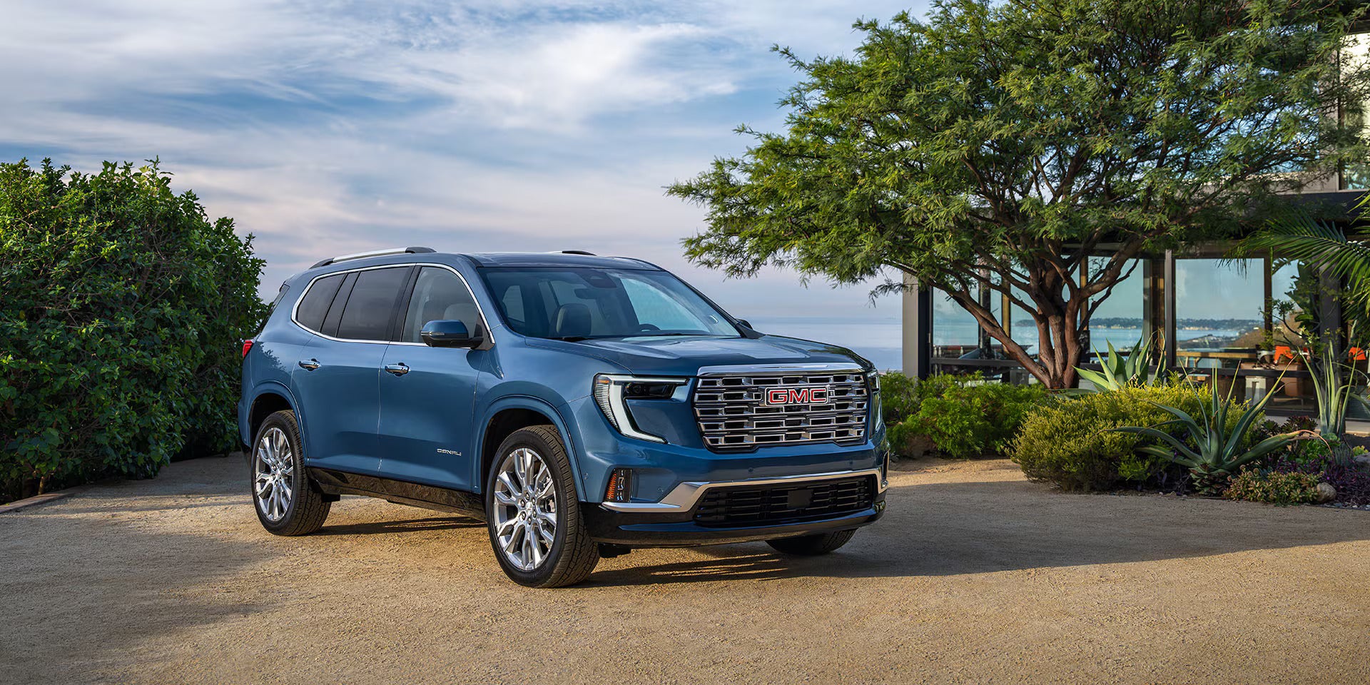 a blue 2026 gmc acadia suv parked next to an overlook