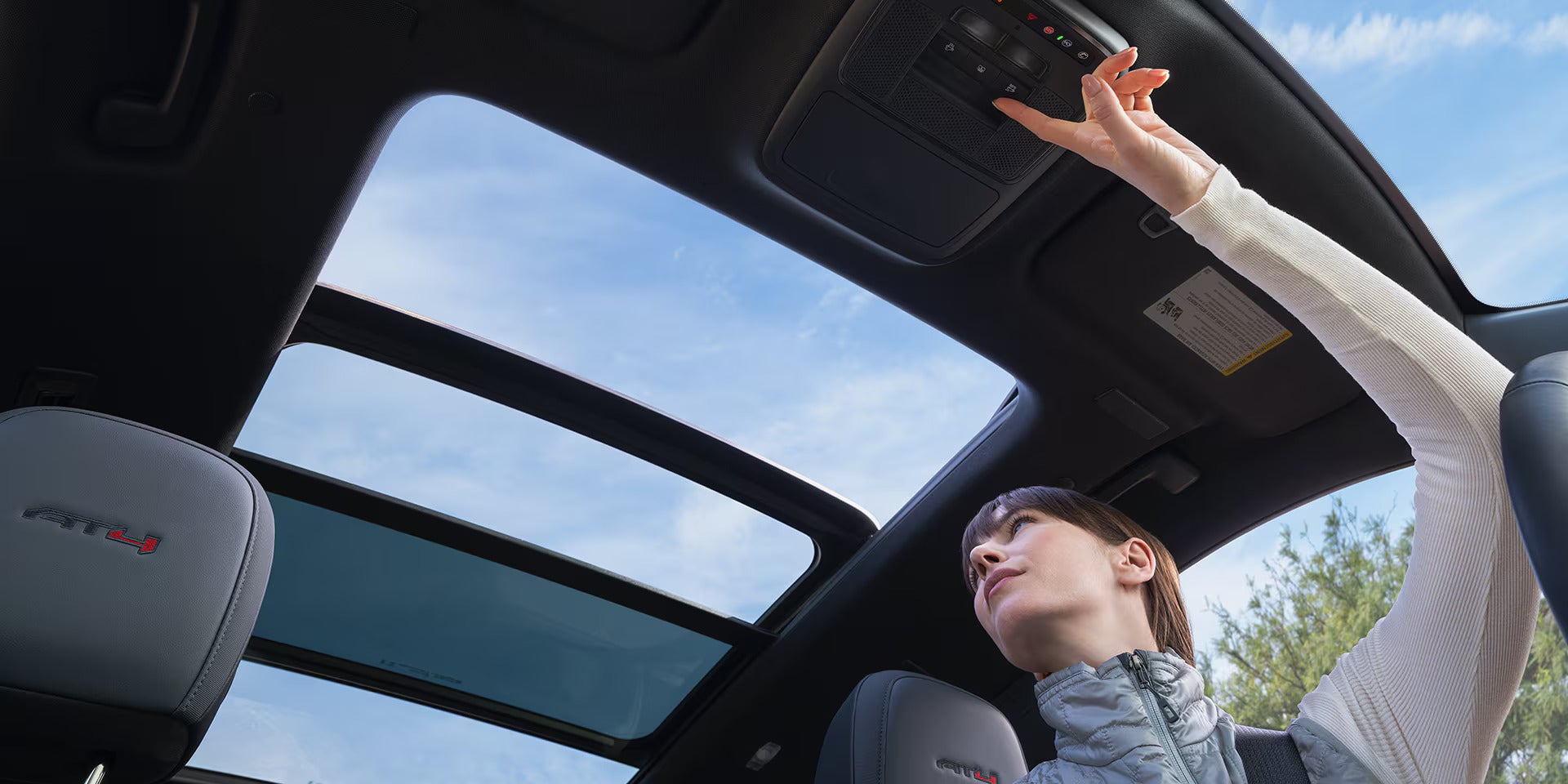 a woman opening the sunroof in a 2026 gmc acadia