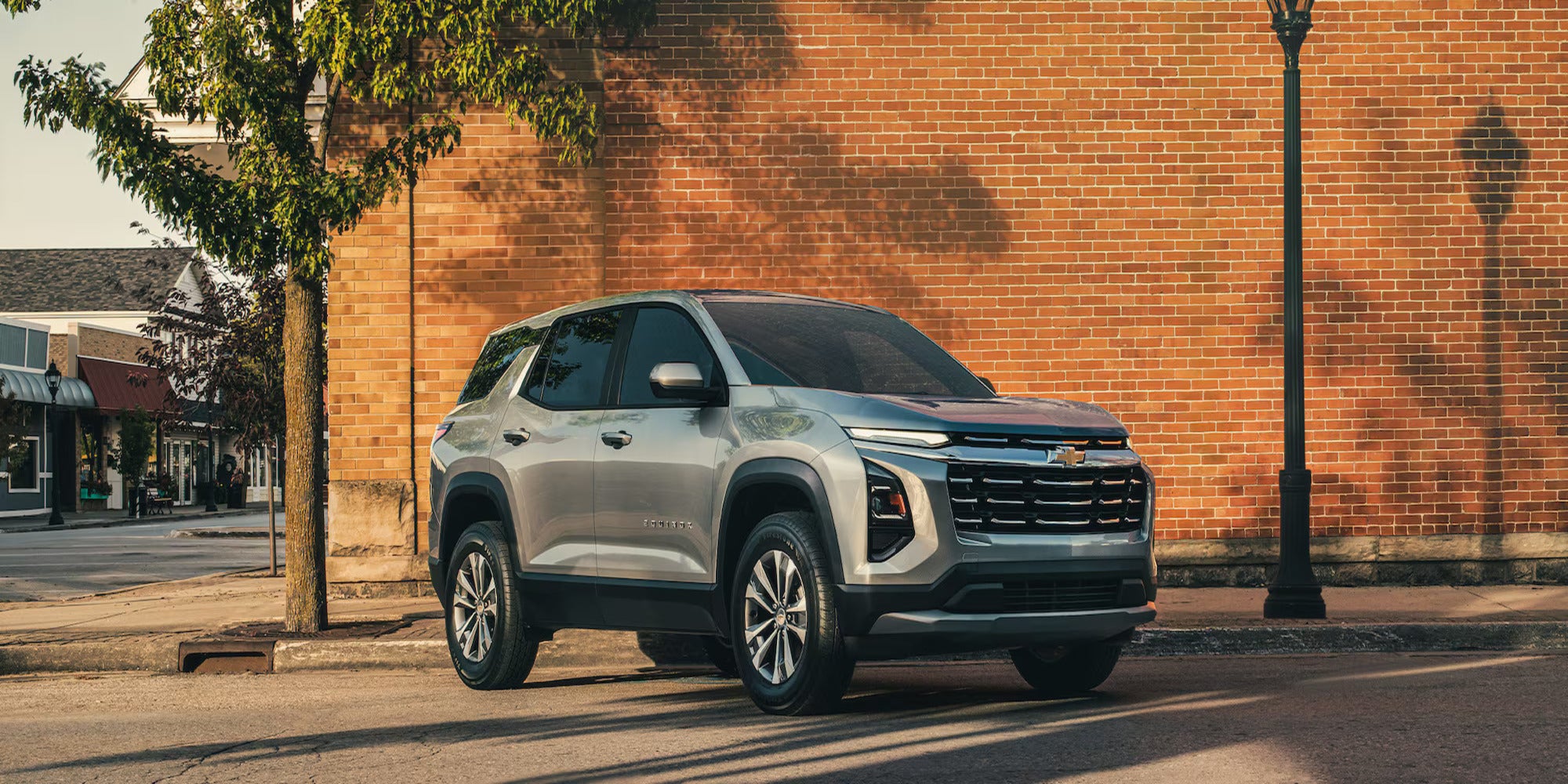 A silver car parked in front of a brick wall.