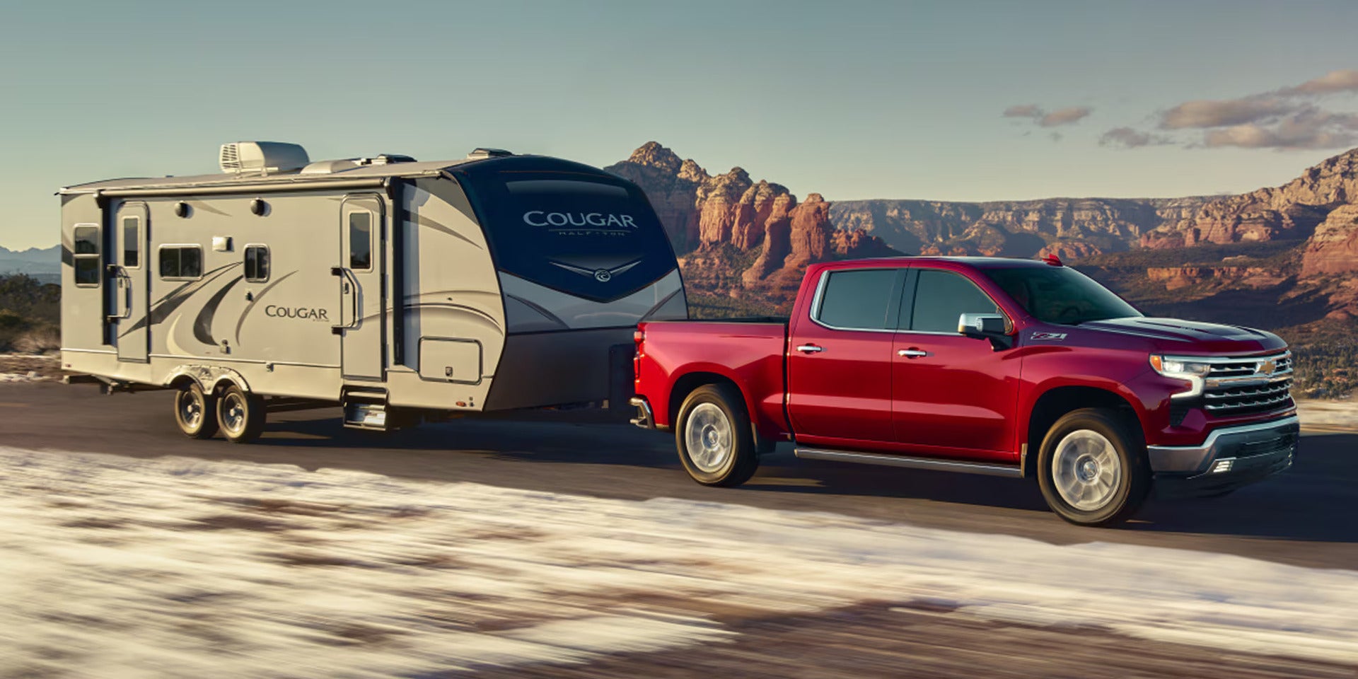 a red silverado 1500 hauling a camper trailer