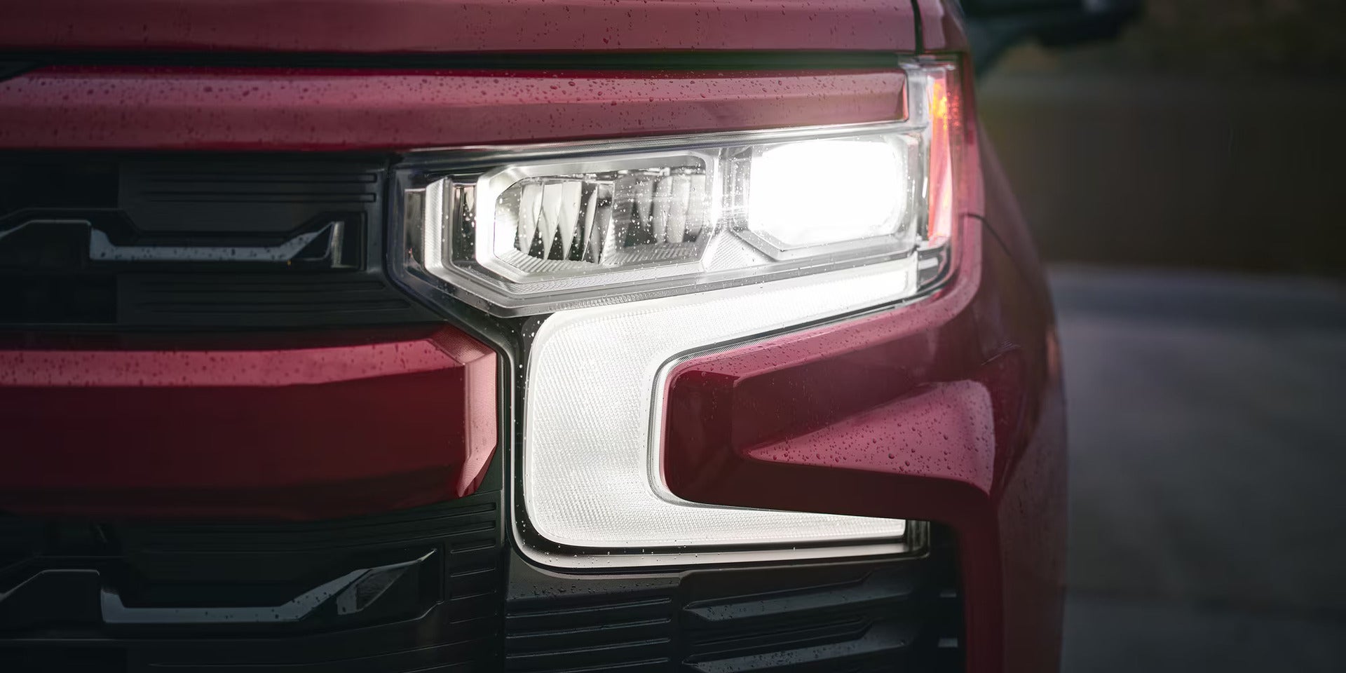 front LED headlight shown up close in a red 2026 silverado 1500