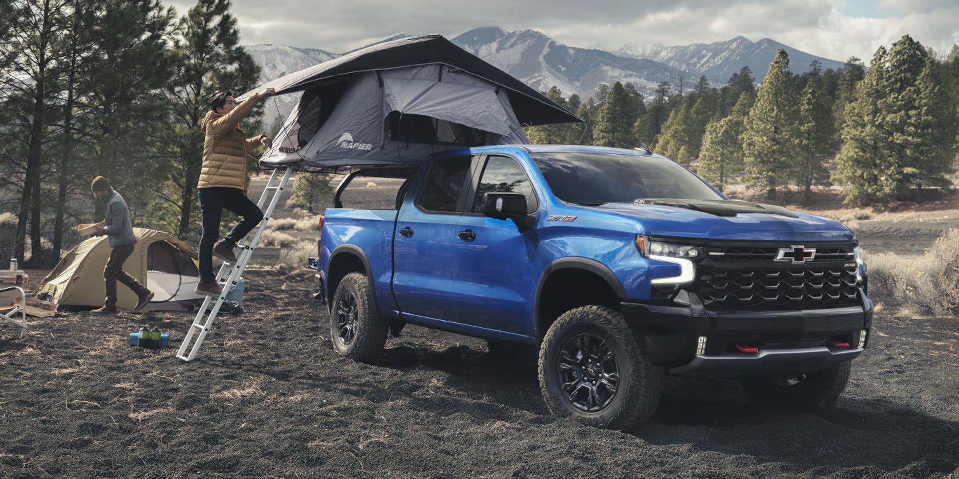 a blue 2026 silverado 1500 with a pop up tent in the bed of the truck