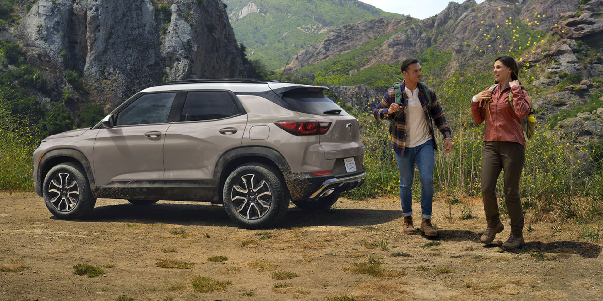 a couple about to go hiking next to a 2026 trailblazer parked in the mountains