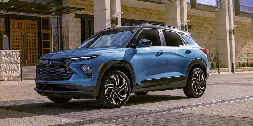 a blue trailblazer parked next to a building