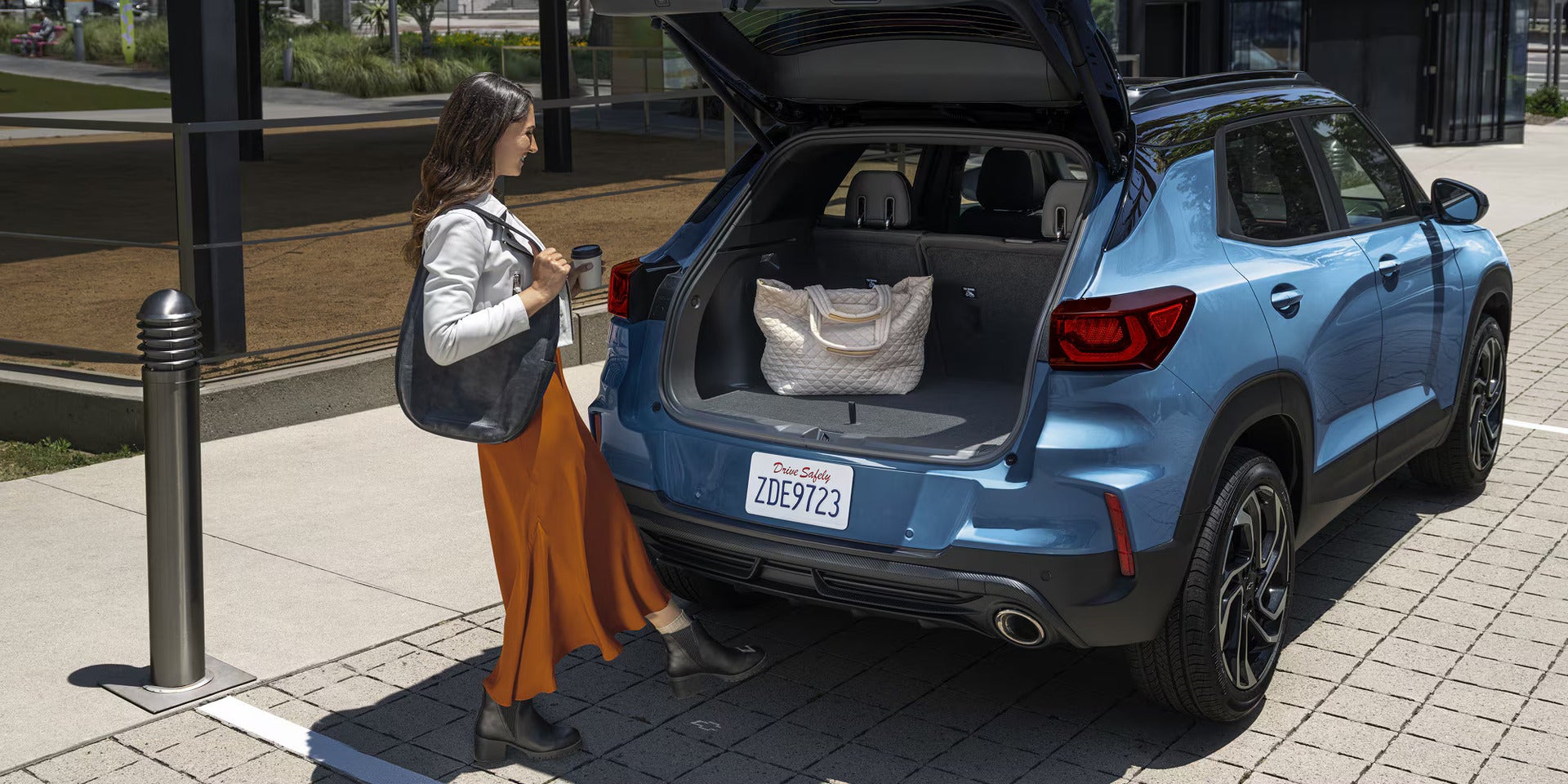 a lady putting a bag into the back of a 2026 blue chevy trailblazer