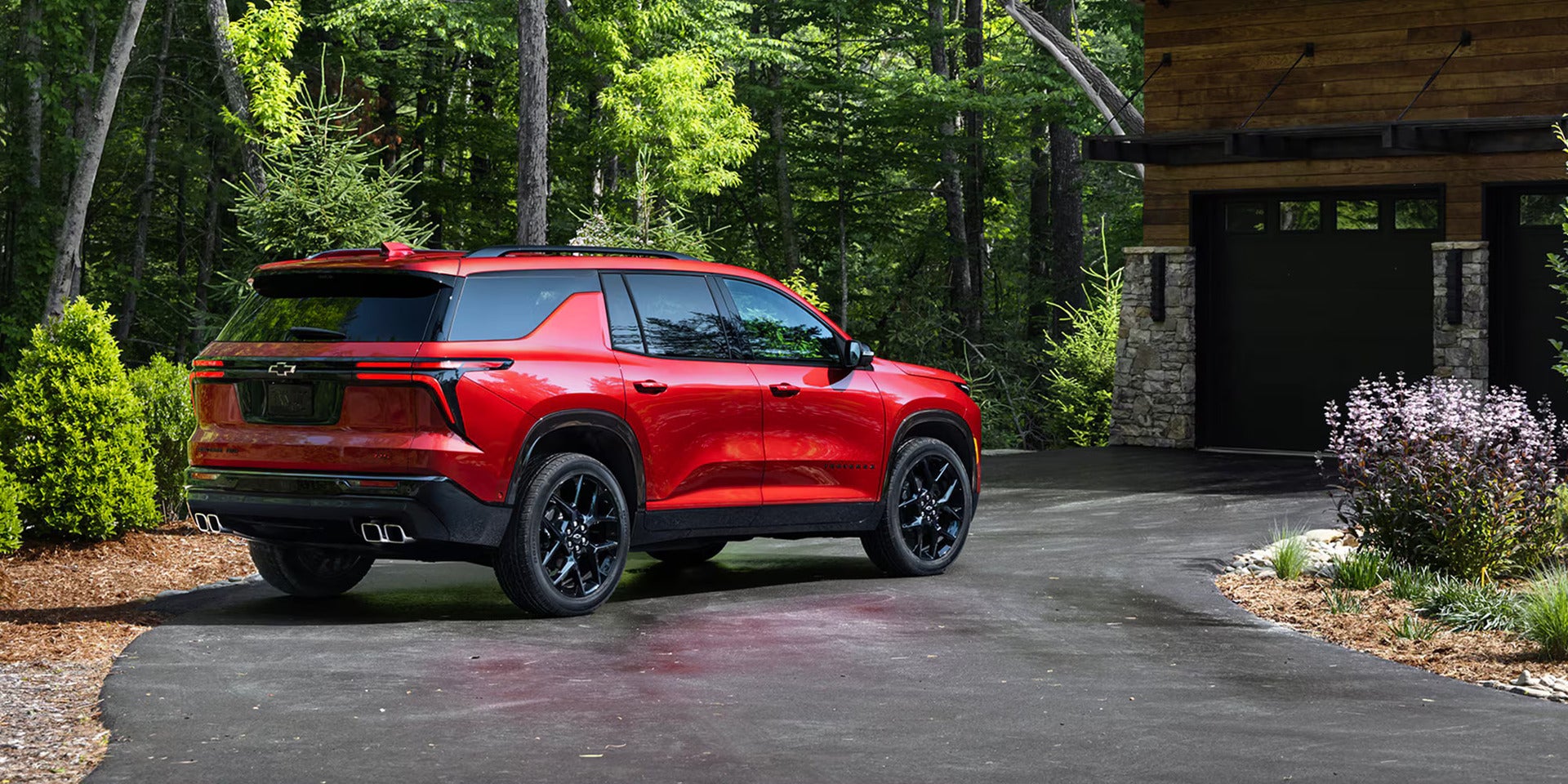 the back and passenger side showcased on a red chevy traverse parked next to a house in the woods