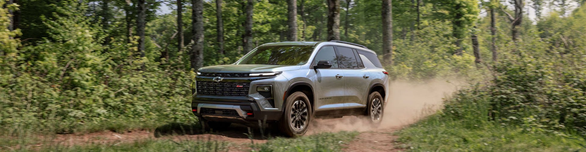 a 2026 chevy traverse driving up a mountain pass with trees and rocks in the background